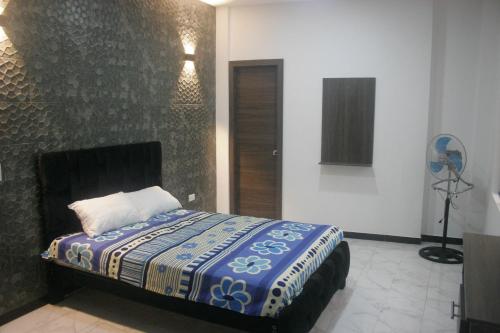 a bedroom with a bed with a blue and white blanket at Casa cerca del Terminal de SANTO DOMINGO in Santo Domingo de los Colorados