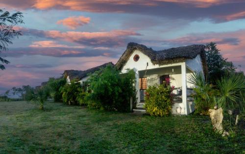 a small white house with a thatched roof at CABAÑAS THAJU in El Naranjito