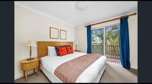 a bedroom with a bed and a window with blue curtains at Villa 2br Shiraz Villa located within Cypress Lakes Resort in Pokolbin