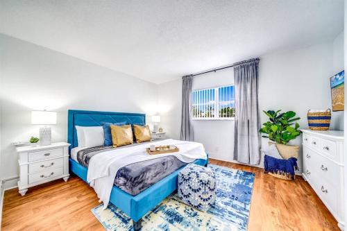 sypialnia z niebieskim łóżkiem i oknem w obiekcie King Water View - No Extra Fees - Palm Wave Says w mieście Coconut Creek