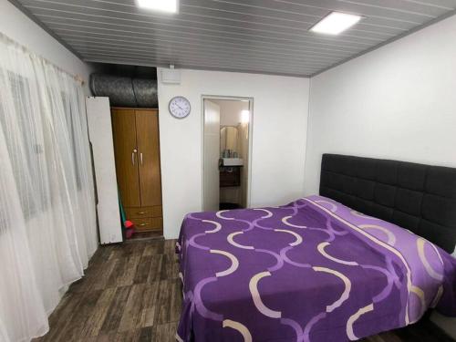 a bedroom with a purple bed and a clock on the wall at Alojamiento Donatello in Durazno