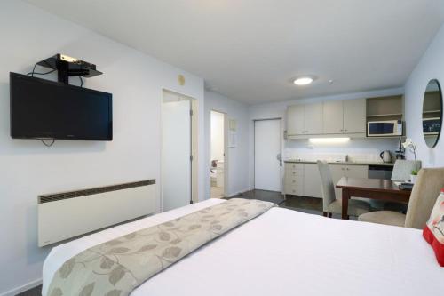 a bedroom with a bed with a television on the wall at Chelsea Park Motor Lodge in Nelson