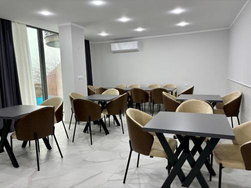 a dining room with tables and chairs and windows at Hillside Inn in Batumi