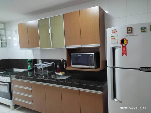 uma cozinha com um frigorífico branco e um micro-ondas em Apartamento encantador a 250 m da Praia do Forte em Cabo Frio