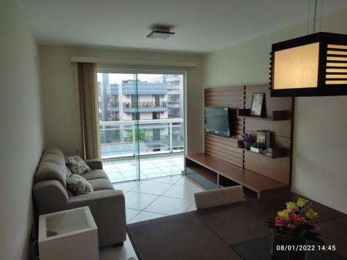 uma sala de estar com um sofá e uma grande janela em Apartamento encantador a 250 m da Praia do Forte em Cabo Frio