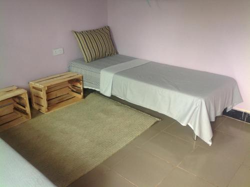een kamer met een bed, een stoel en een tapijt bij Kimashuku permaculture garden in Weru Weru