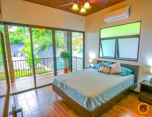 sypialnia z dużym łóżkiem i balkonem w obiekcie Modern Mountain View Home by Nauyaca Waterfall w mieście Platanillo