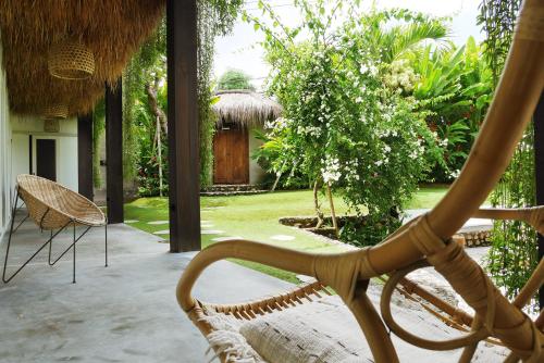 a porch with a rattan chair and a house at Amar Boutique Hotel in Canggu