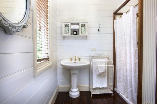 a white bathroom with a sink and a window at Winter Rose - gorgeous gardens sleeps 5 in Olinda