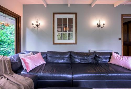 a black leather couch in a living room with pink pillows at Winter Rose - gorgeous gardens sleeps 5 in Olinda
