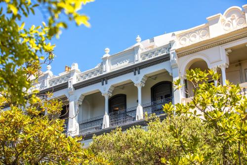 an ornate white building with trees in the foreground at Holiday Inn Sydney Potts Point in Sydney