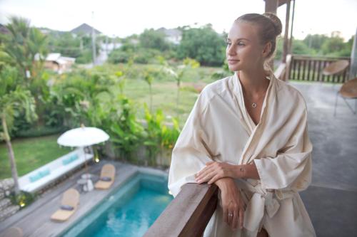 a woman standing on a balcony next to a swimming pool at Amar Boutique Hotel in Canggu