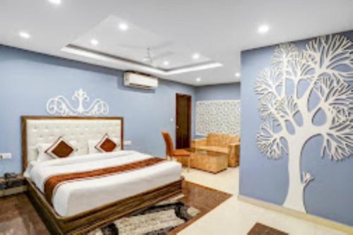 a bedroom with a bed with a tree painted on the wall at Hotel Green Embassy Meerut in Meerut