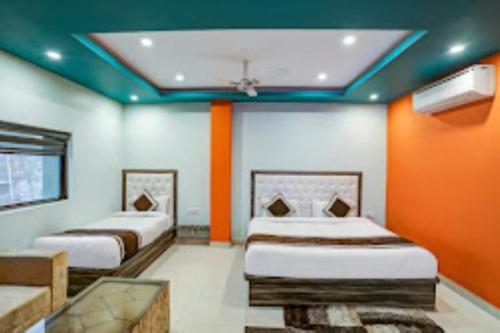 Duas camas num quarto com tectos laranja e azul em Hotel Green Embassy Meerut em Meerut