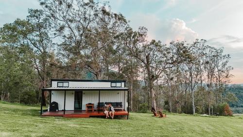 a house on a hill with two people standing in the grass at Tiny Zoe in Mount George