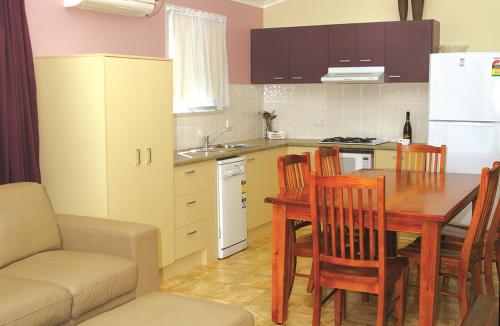 a kitchen with a table and chairs and a kitchen with a sink at Smugglers Cove Holiday Village in Forster