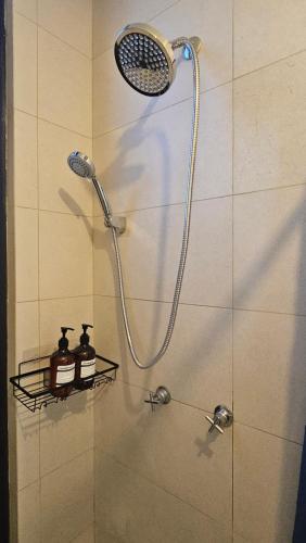 a shower with a shower head and two bottles on a shelf at Depto Centro de Monterrey by tuhost in Monterrey