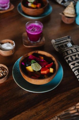 a wooden table with a bowl of fruit on a plate at Amar Boutique Hotel in Canggu