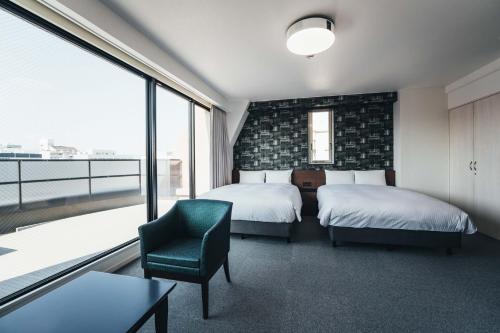 TAPSTAY HOTEL - Vacation STAY 35227v في ساغا: غرفة نوم بسريرين وكرسي ونافذة