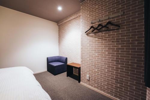 佐賀市にあるTAPSTAY HOTEL - Vacation STAY 35238vのレンガの壁と青い椅子が備わるベッドルーム1室