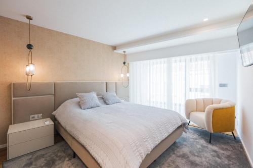a bedroom with a large bed and a chair at SeaLux Apartment (Seaside) in São Roque