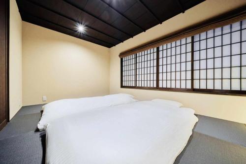 a bedroom with a white bed and a window at Kyoto Machiya Zeniyacho in Kyoto