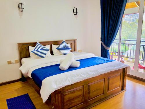 a bedroom with a large bed with blue and white pillows at Star Holiday Home in Nuwara Eliya