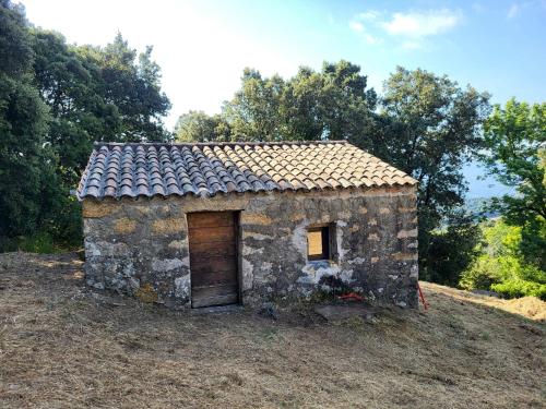 un pequeño edificio de piedra con una puerta en una colina en L anghjuledda 2 en Grosseto-Prugna