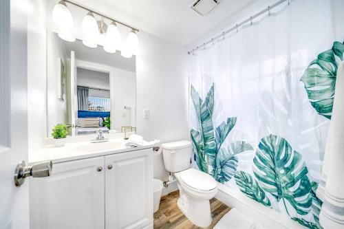 La salle de bains blanche est pourvue de toilettes et d'un rideau de douche. dans l'établissement Adorable Condo in Peaceful Area - Palm Wave Says, à Coconut Creek