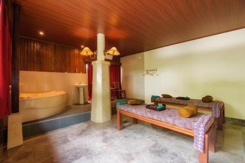 a bathroom with a tub and a bench and a sink at Champlung Sari Villa & Spa Ubud in Ubud