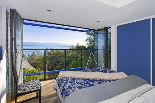 um quarto com uma cama e uma grande janela em Coastal Escape em Nelson