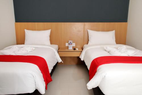 1 dormitorio con 2 camas con sábanas rojas y blancas en Kiyana Premiere Hotel Batang en Pekalongan