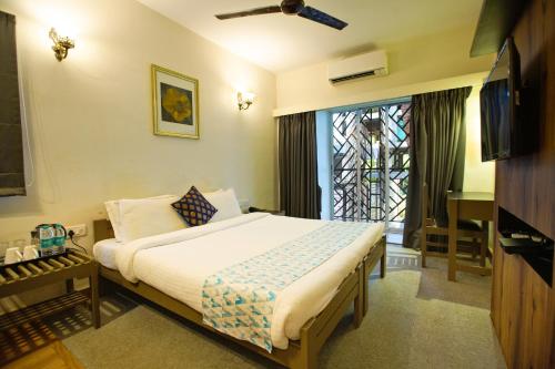 a bedroom with a bed and a tv and a window at Hotel Bela Goa in Panaji