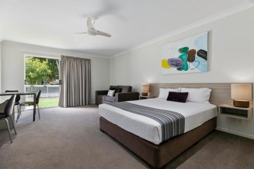 Cette chambre comprend un lit, un bureau et une table. dans l'établissement Beachside Boutique Motel Mackay, à Mackay