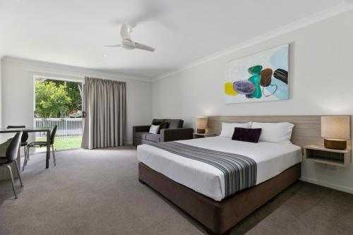 a hotel room with a bed and a desk and a table at Beachside Boutique Motel Mackay in Mackay