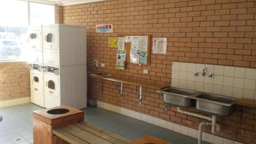 a kitchen with a sink and a refrigerator at Smugglers Cove Holiday Village in Forster