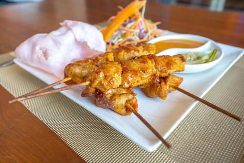 a plate of food with chicken skewers and dipping sauce at Chitwan Midtown Hotel in Bharatpur