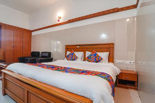 a bedroom with a large bed and a black chair at FabHotel Skyry I in Coimbatore