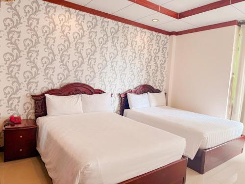 a bedroom with two beds and a wall with wallpaper at Phúc Đạt Hotel in Vung Tau