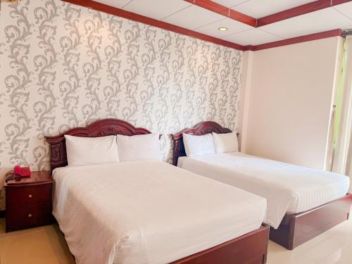 a bedroom with two beds and a wall with wallpaper at Phúc Đạt Hotel in Vung Tau