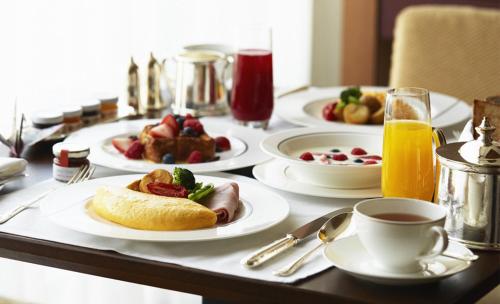 a table with plates of food and cups of orange juice at Holiday Express Hotel Kampala in Kampala