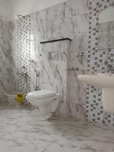 a white bathroom with a toilet and a sink at Savi's home stay in Ooty