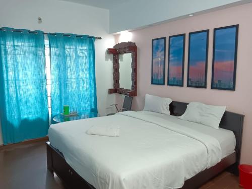 a bedroom with a large white bed with blue curtains at Savi's home stay in Ooty