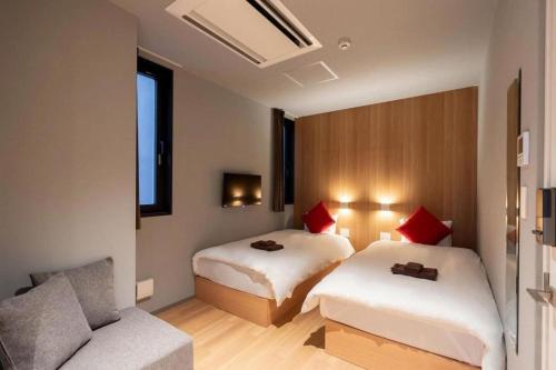 大阪市にあるZONE SHINSAIBASHI WESTのベッド2台とソファが備わるホテルルームです。