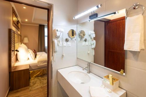 uma casa de banho com um lavatório, um espelho e uma cama em زمان هوم لاند Zaman Homeland em Taif