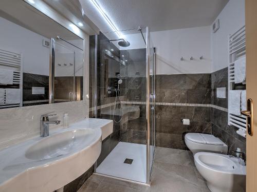 a bathroom with two sinks and a shower and a toilet at Hotel Madonna delle Nevi in Folgarida