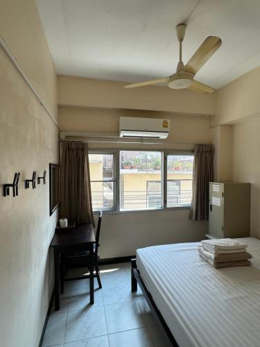 a bedroom with a bed and a desk and a window at KC guest house in Bangkok