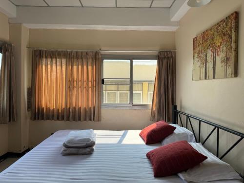 a bedroom with a bed with red pillows and a window at KC guest house in Bangkok