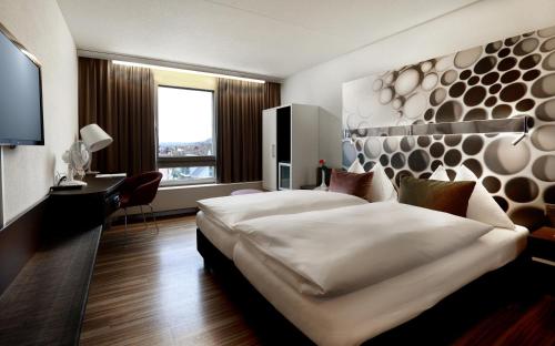 ein Hotelzimmer mit einem großen Bett und einem Schreibtisch in der Unterkunft Hotel Thurgauerhof Self-Check-in in Weinfelden