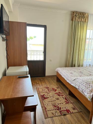 a bedroom with a bed and a table and a window at Guest house Ak Keme in Bosteri